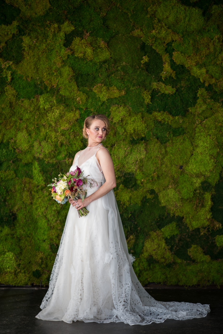 bride and a moss wall