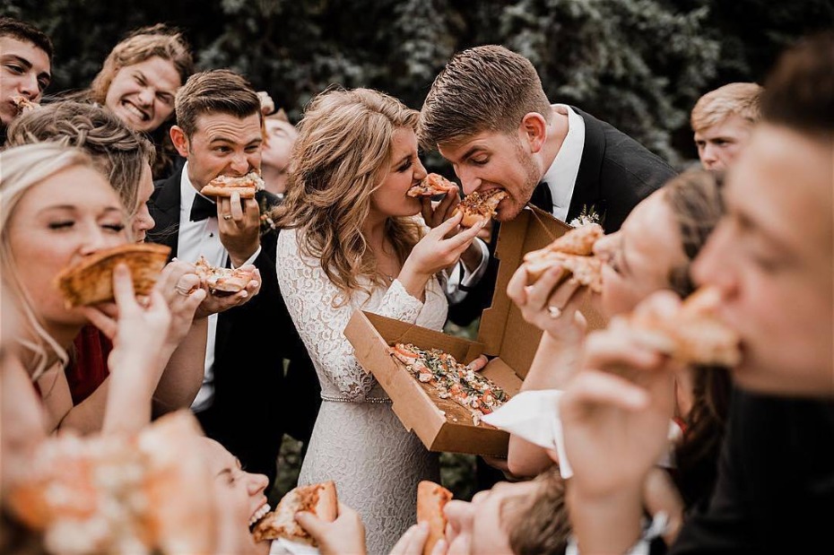 Bride and groom and bridal party taking down pizza