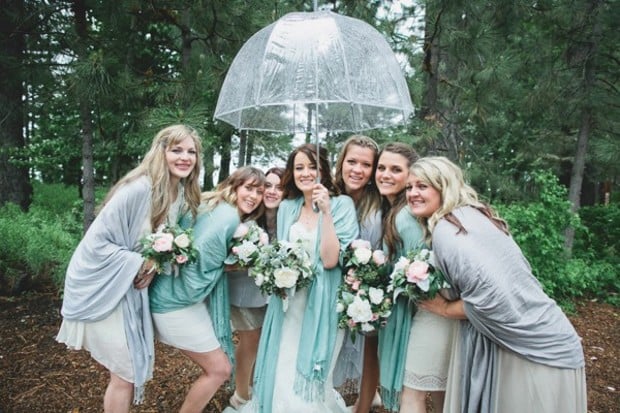 wedding party in cozy shawls under an umbrella in the rain