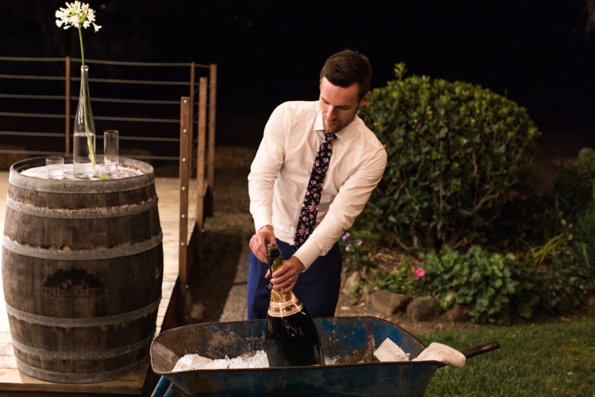 Groom popping a giant Champange bottle