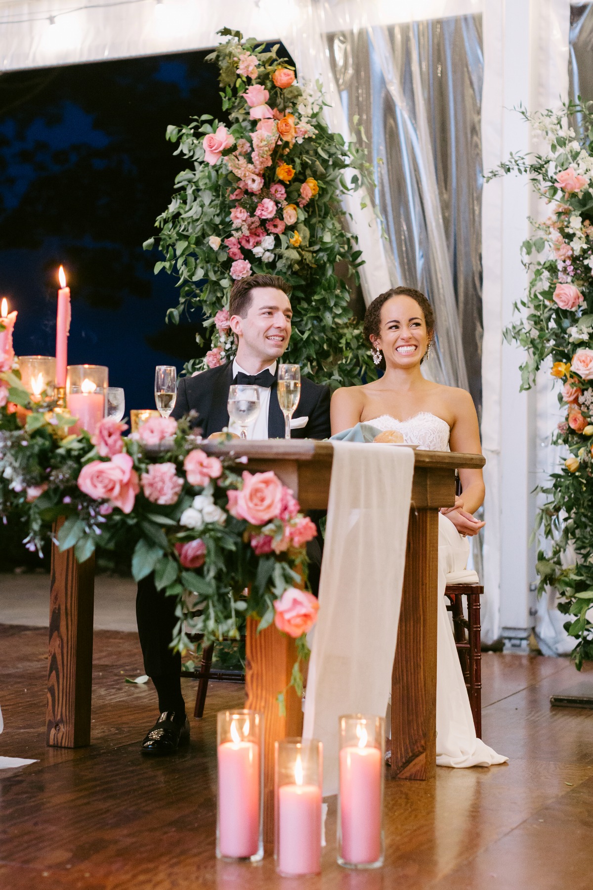 Bride and groom sitting at floral sweetheart table