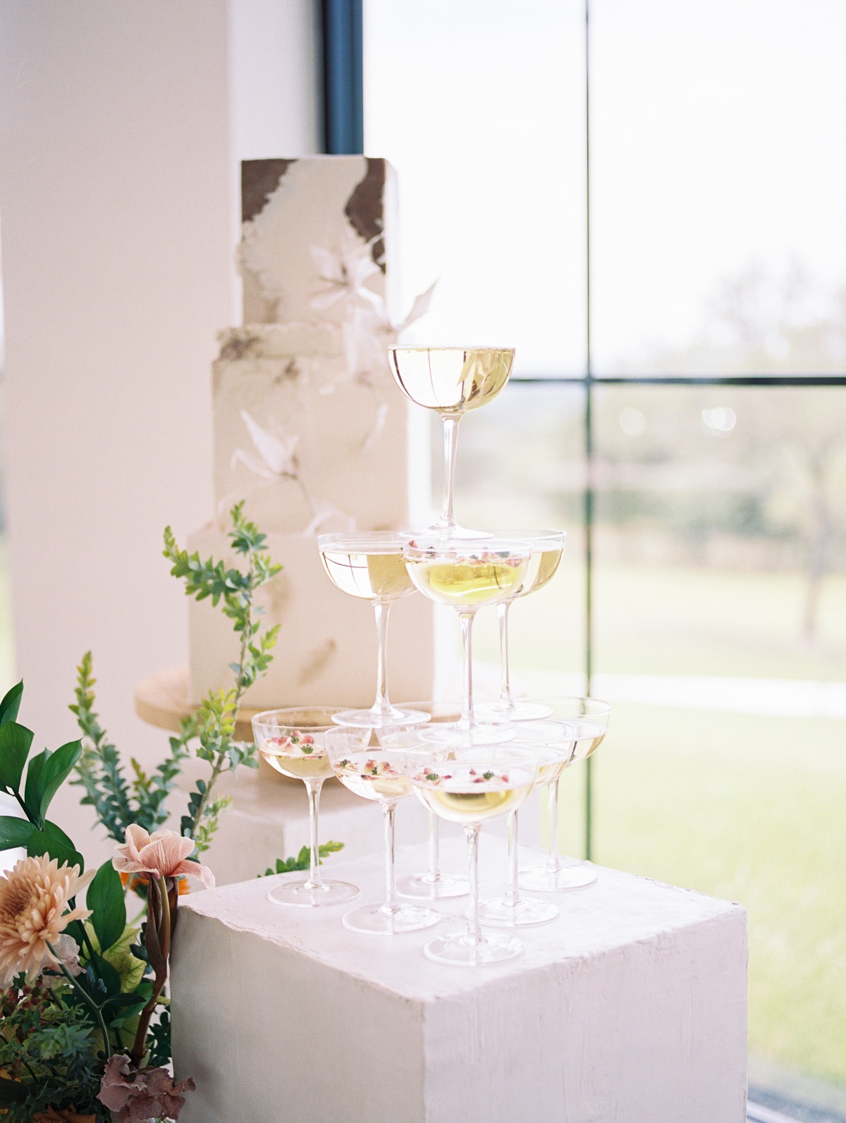 Champagne towers on columns with wedding cake in background