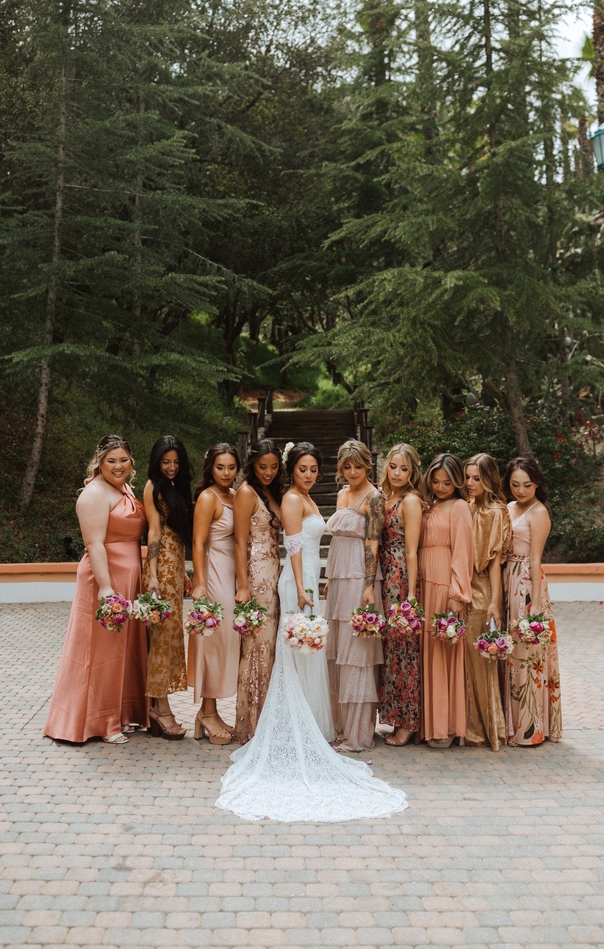 A bride and her bridesmaids in different shades of pink dresses