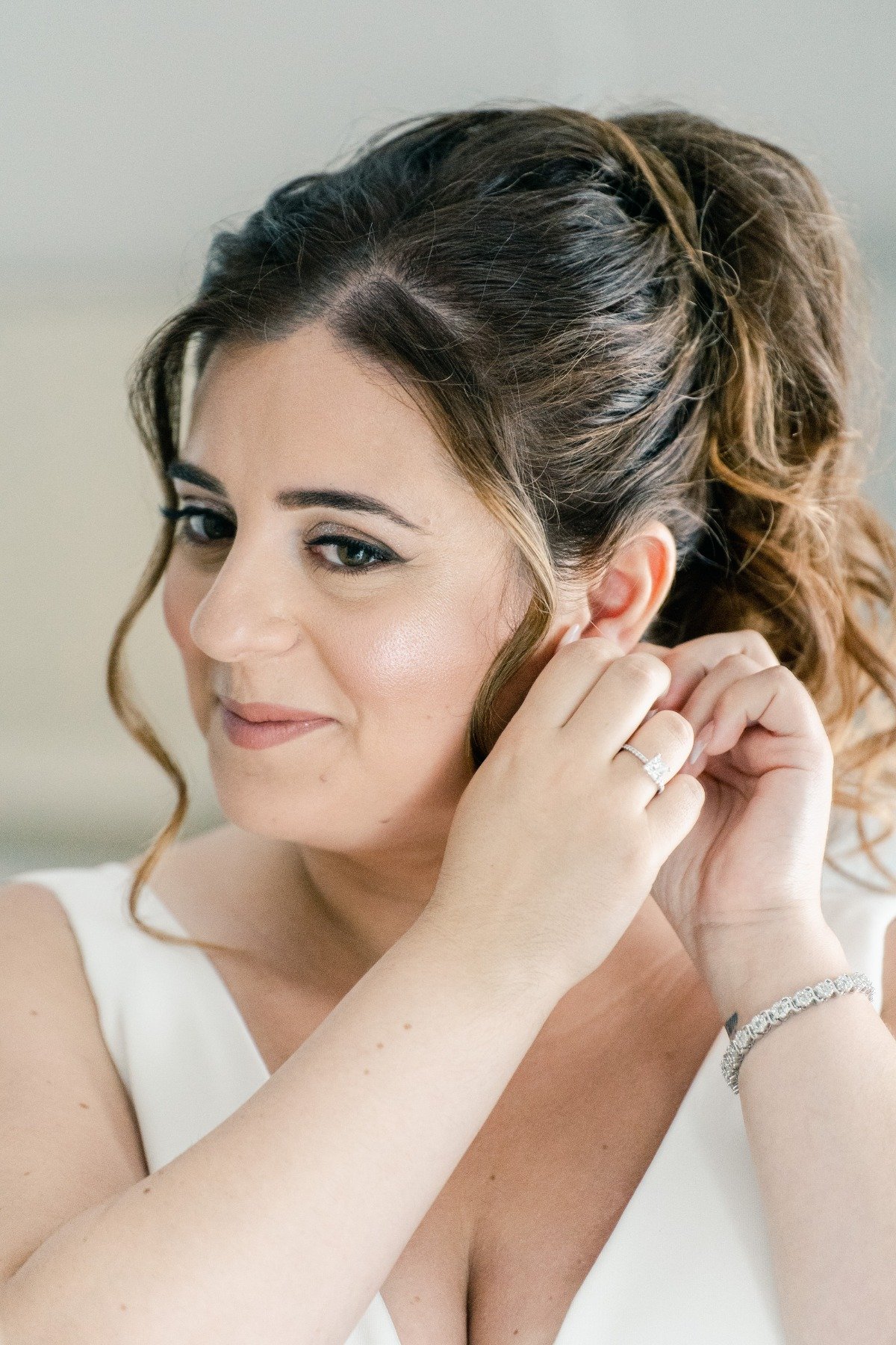 Greek island bride putting on diamond earrings