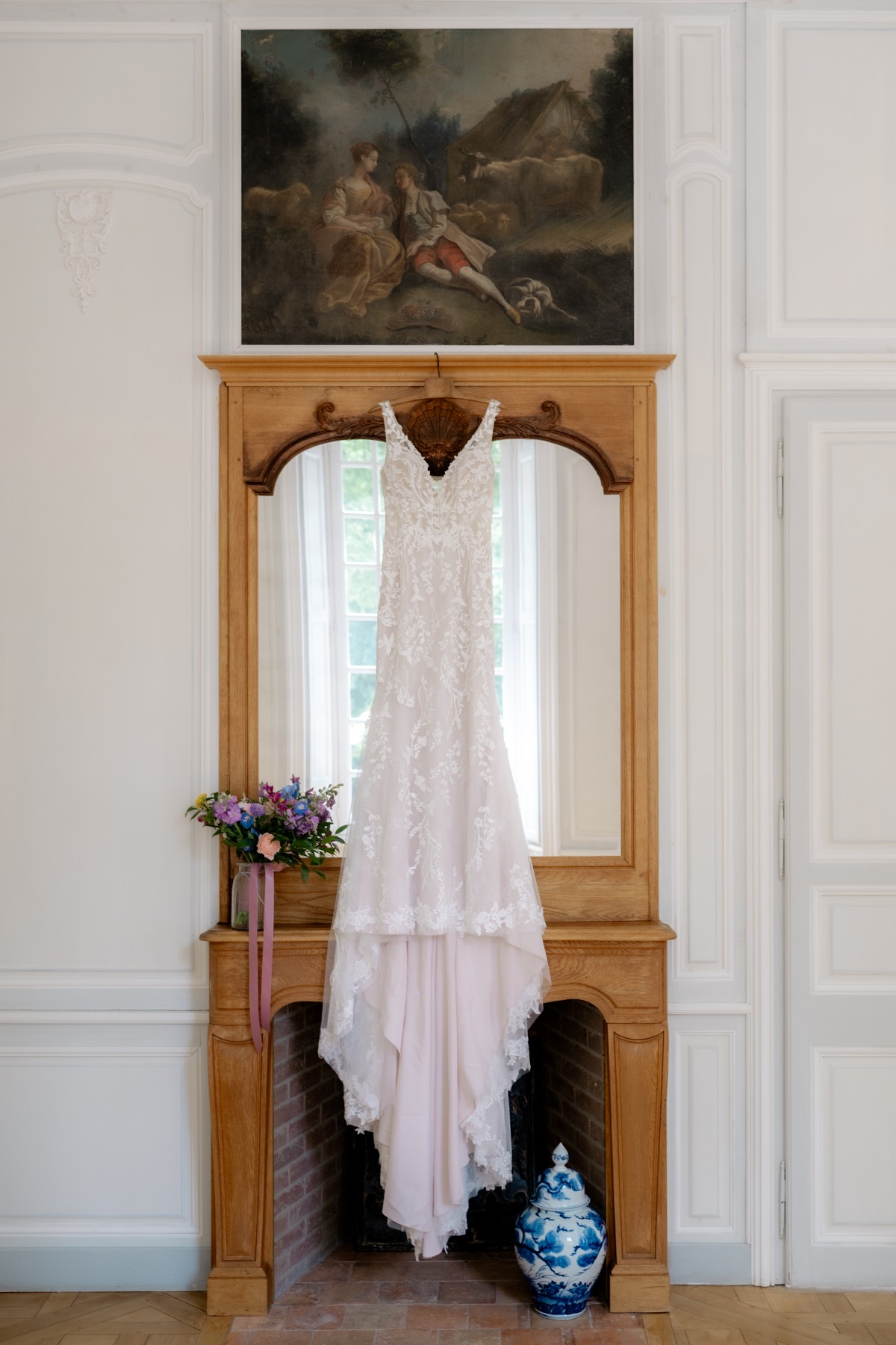 blush and white lace mermaid wedding gown hanging in chateau