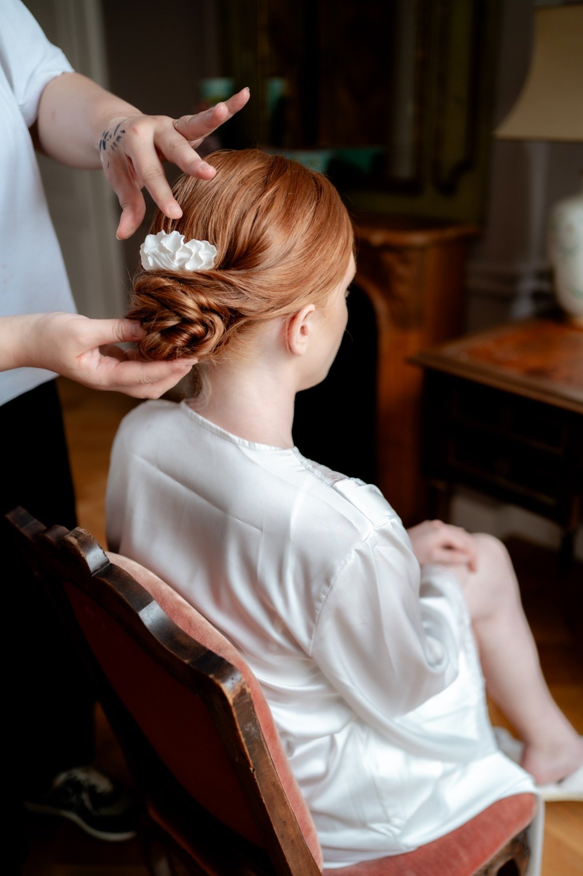 red head bride with bun getting her hair done