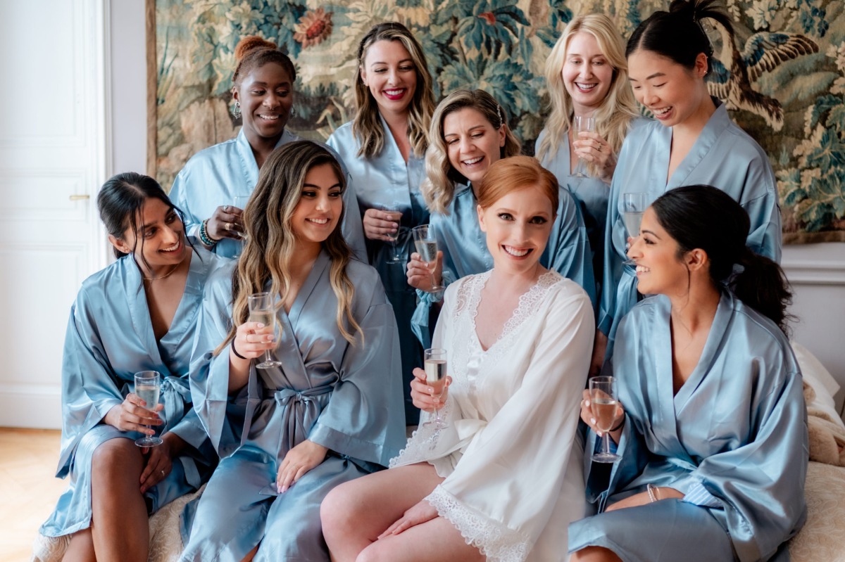 bride in white robe with bridesmaids in pastel blue robes
