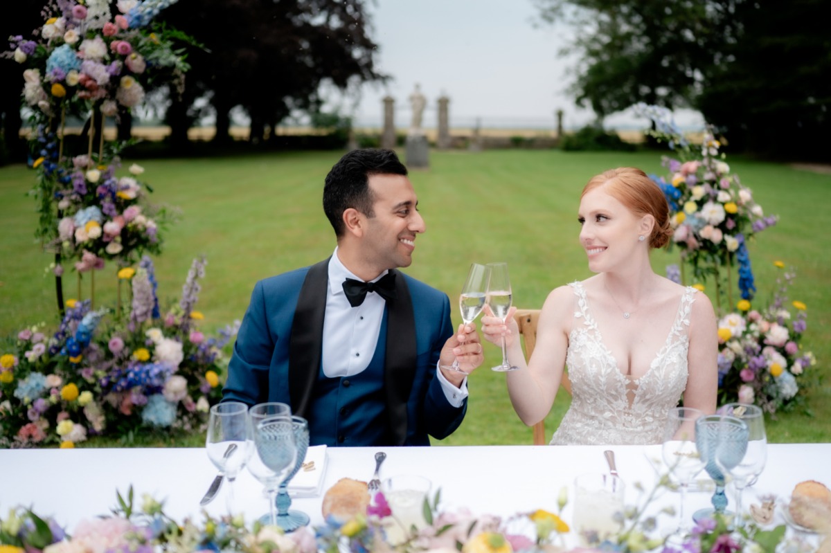 bride and groom toast at colorful sweetheart table 