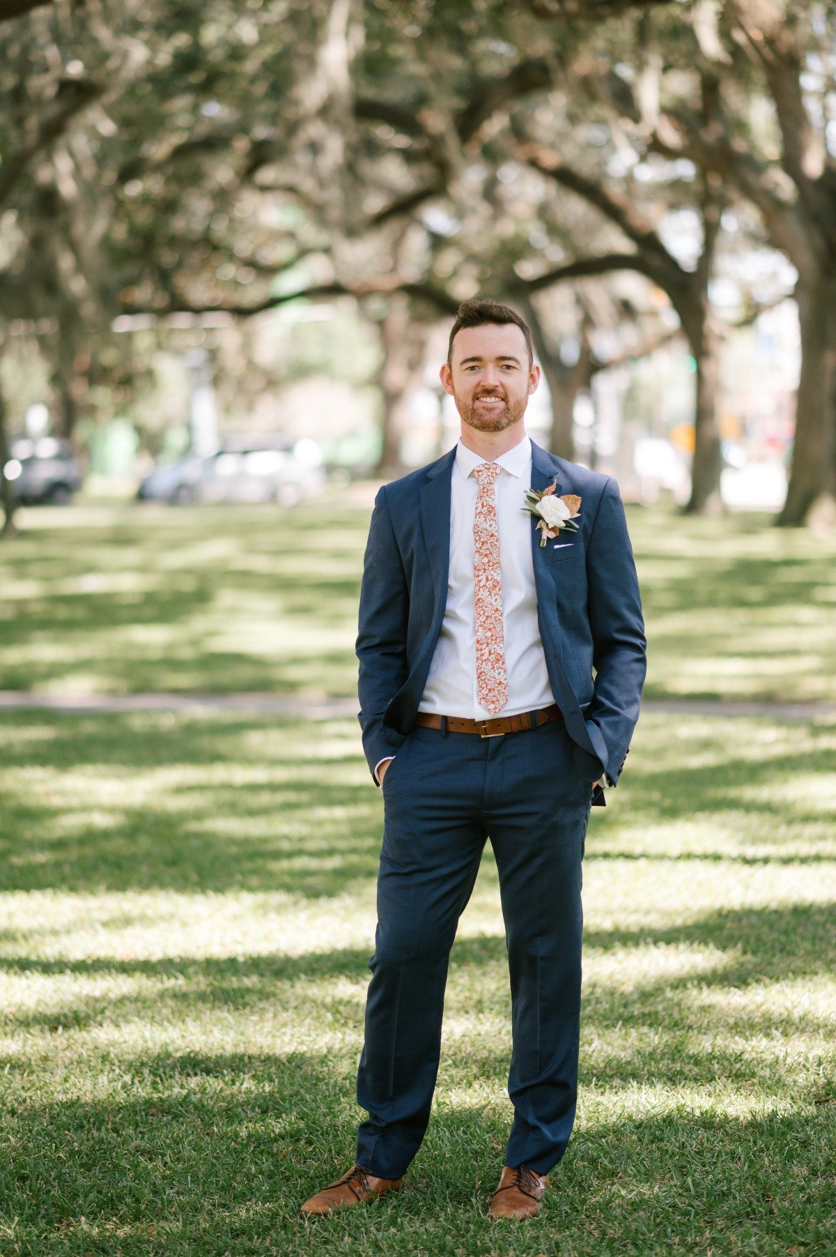 Modern rustic groom in navy suit with orange floral tie