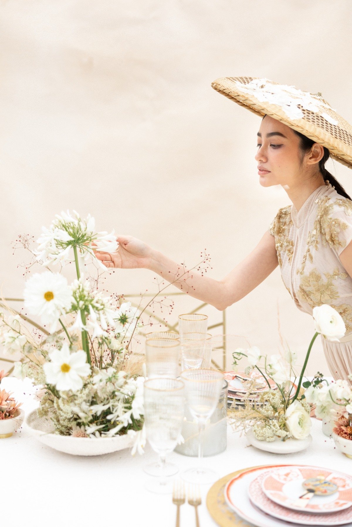 Asian bride adjusting modern flowers at reception table