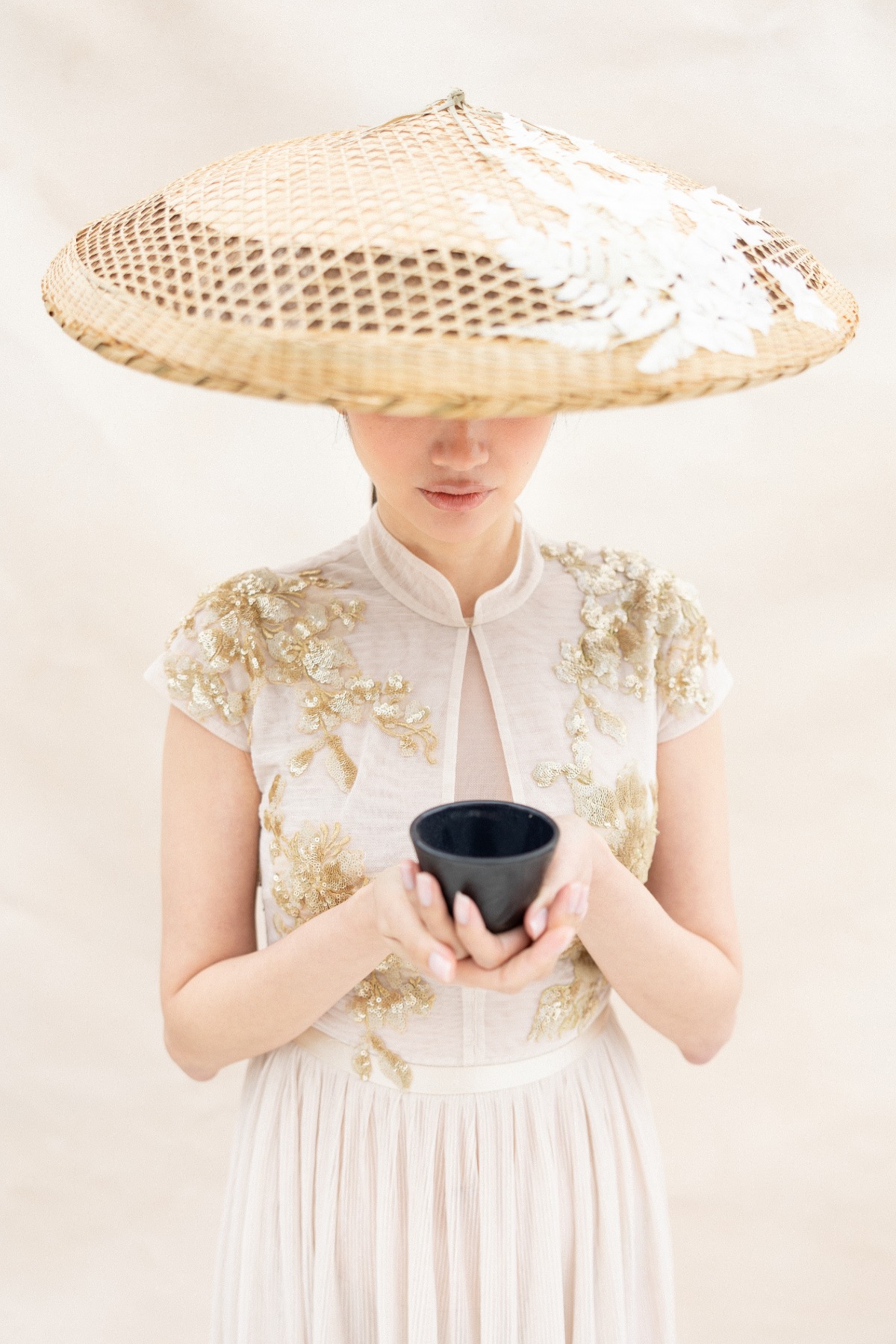 Asian bride in Chinese dress holding black tea cup 