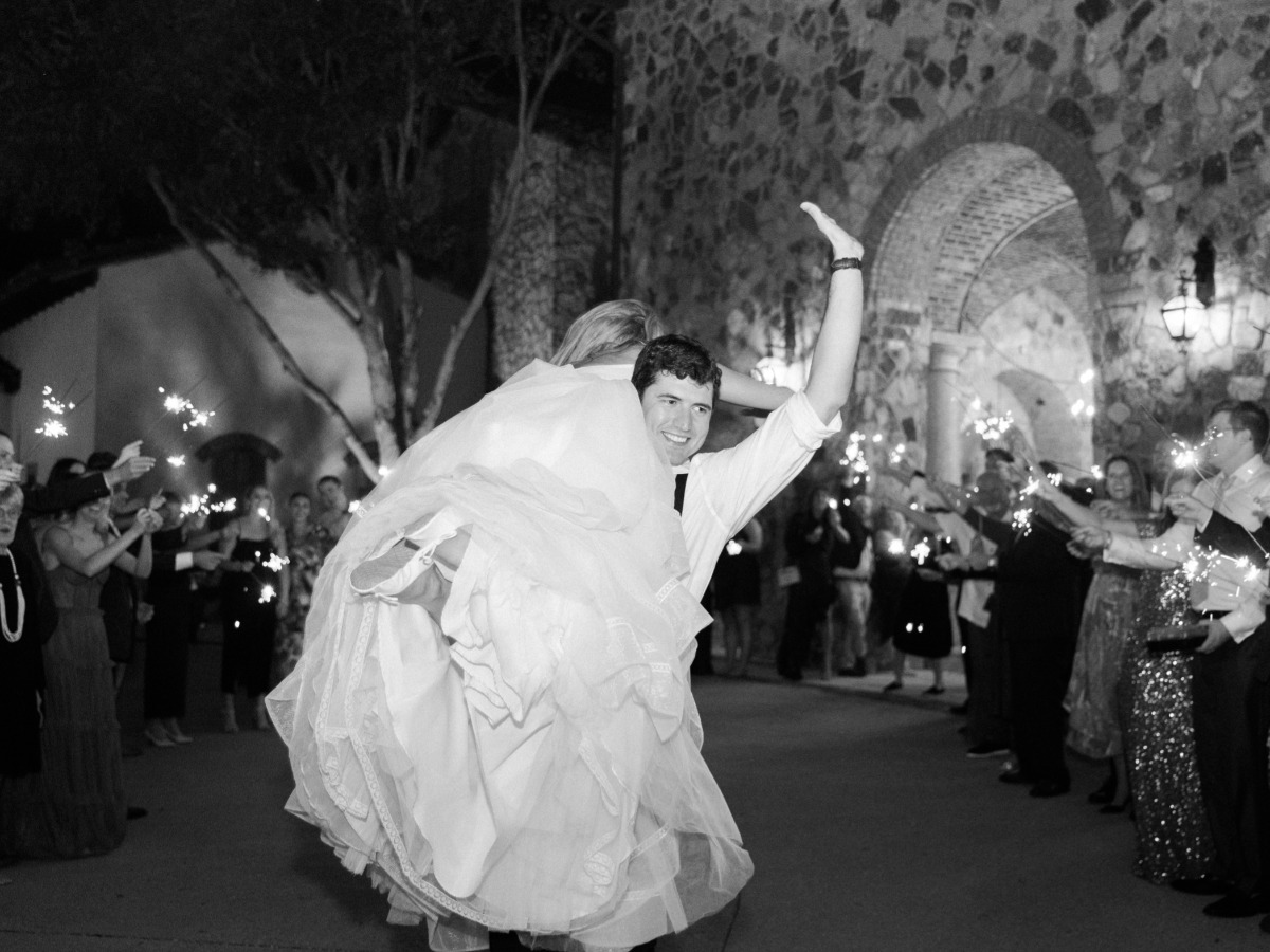 Funny grand exit at wedding with groom carrying bride over shoulder