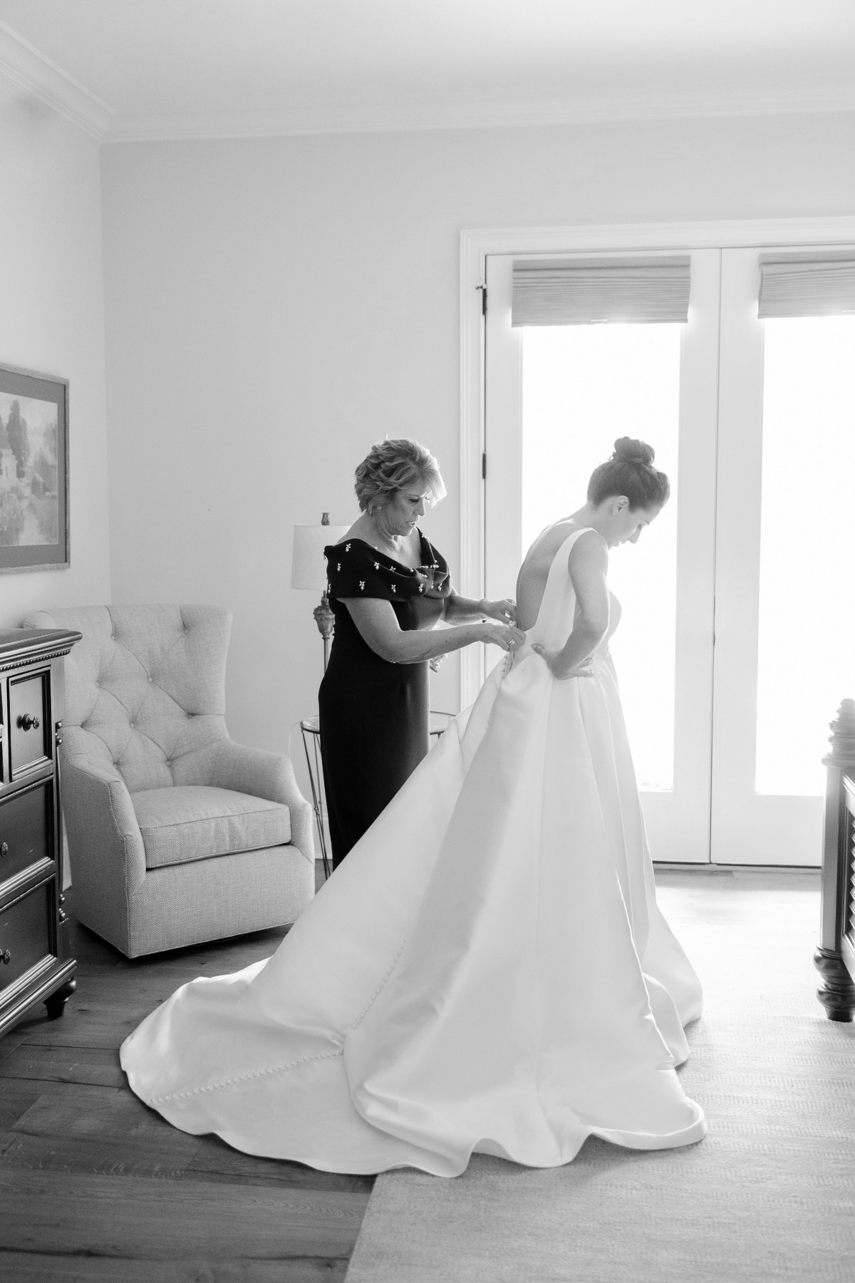 mom zipping bride into wedding gown