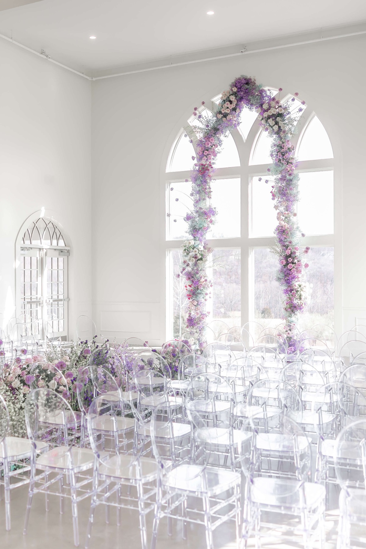 tall floral arch in front of floor to ceiling windows