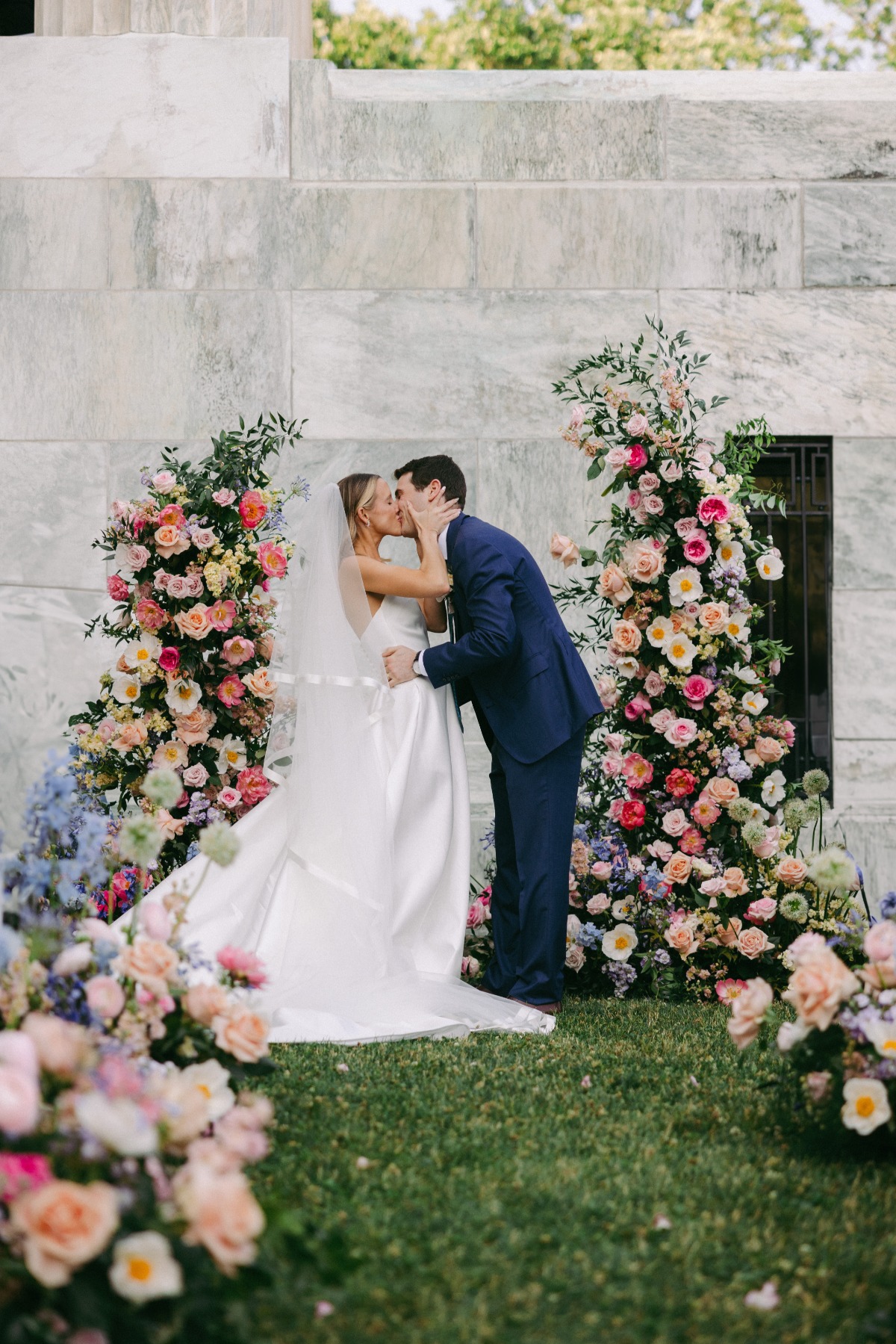 bride and groom kiss at pink outdoor wedding ceremony