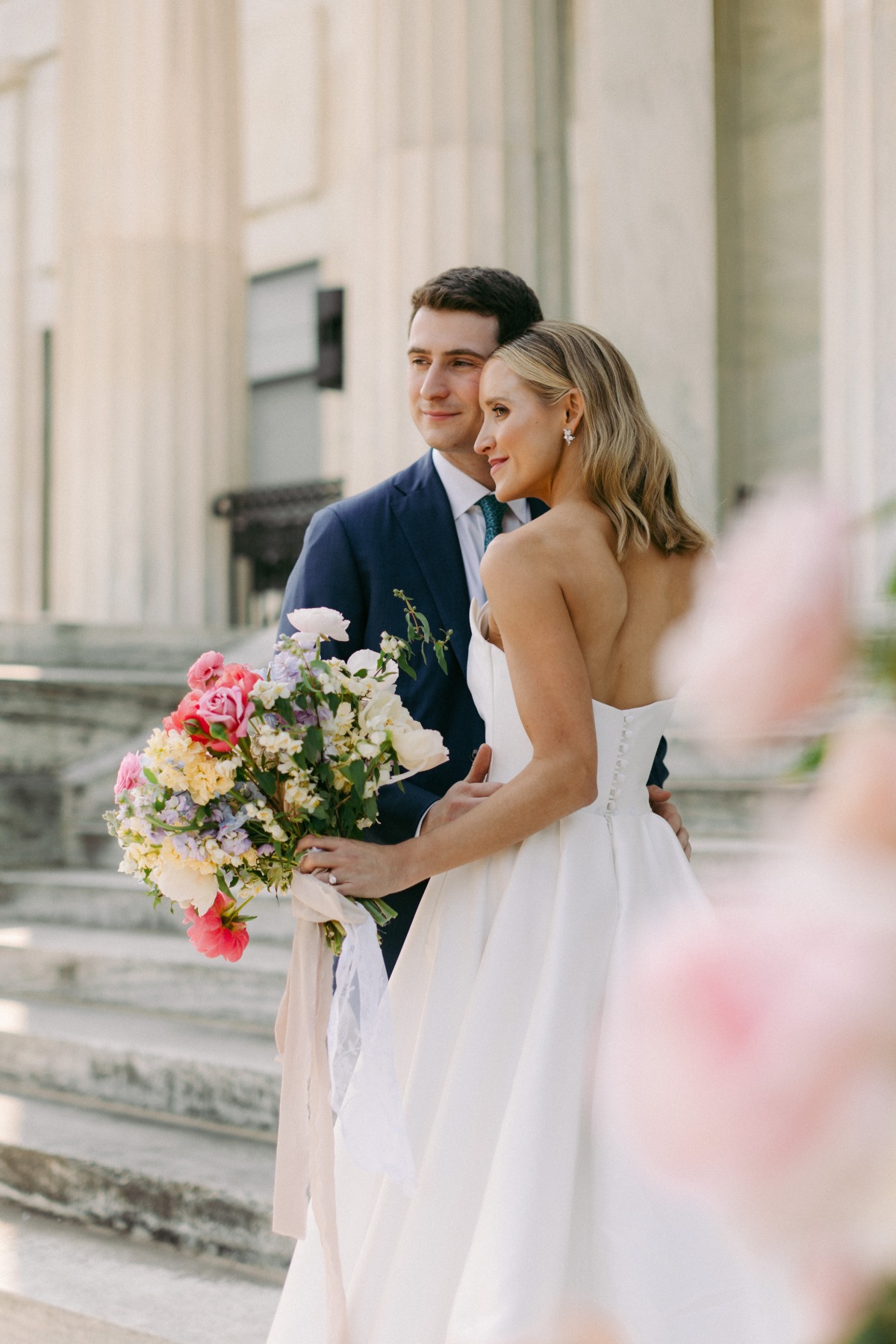 bride and groom pose with columns in the background 