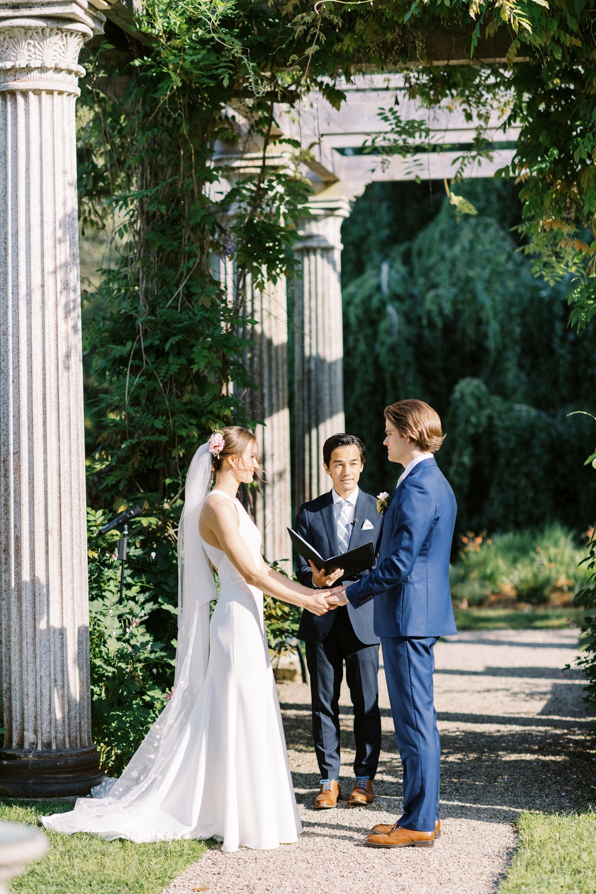 bride and groom exchange vows at garden wedding with columns