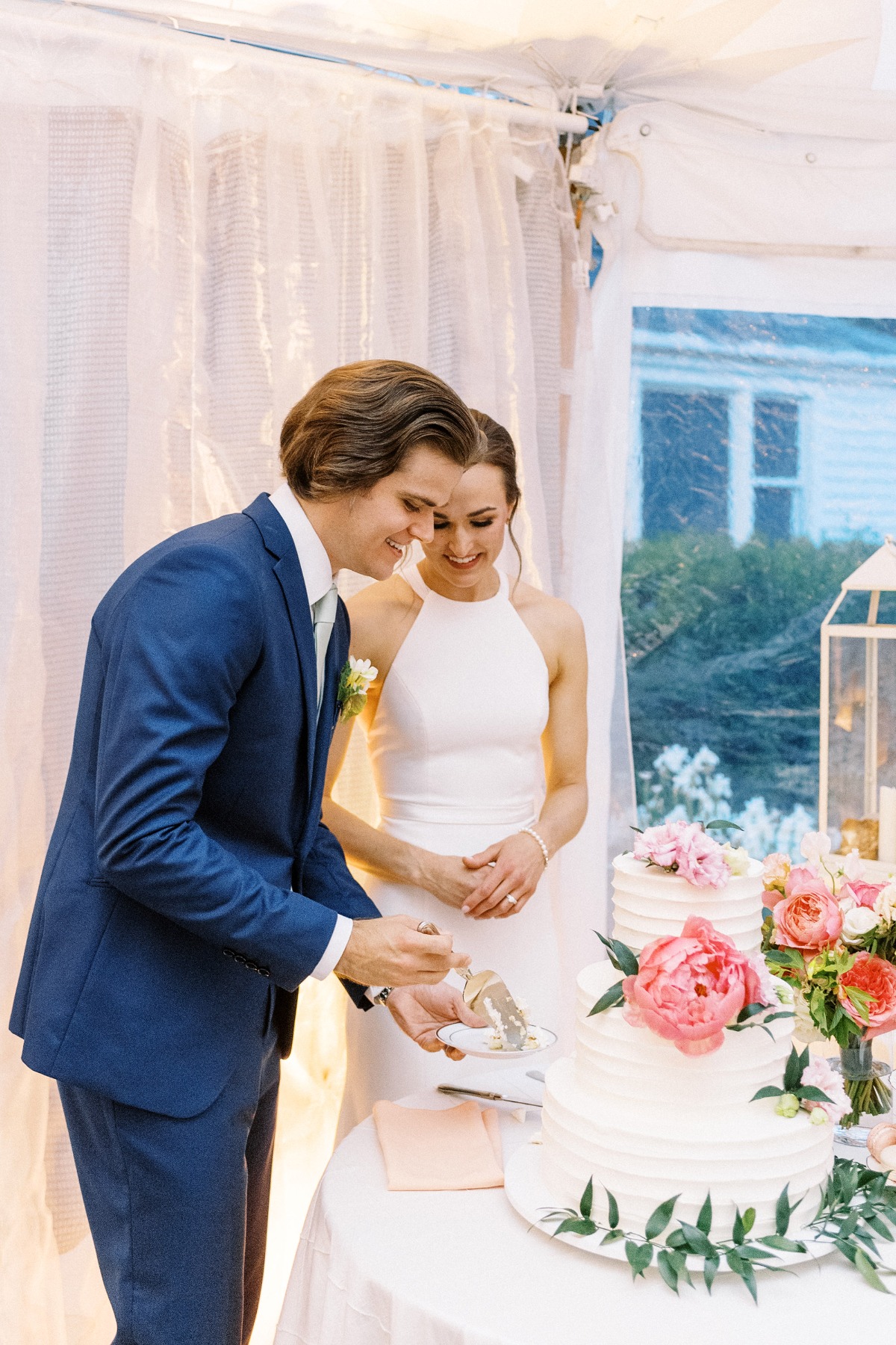 bride and groom cut buttercream cake with peonies