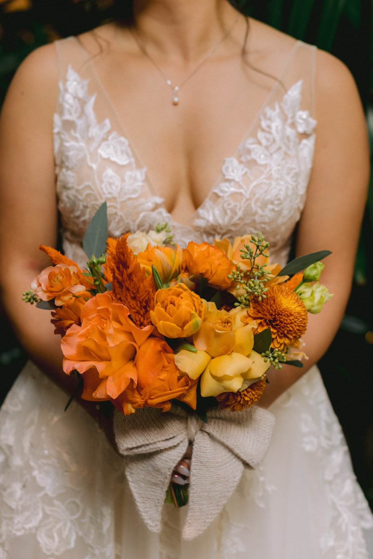 bride in lace dress with orange bouquet