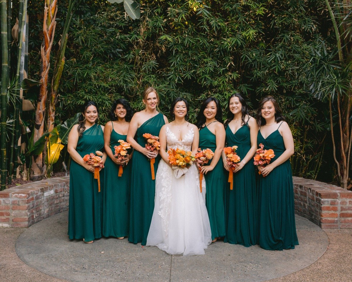 bride in lace and bridesmaids in green with orange boquets