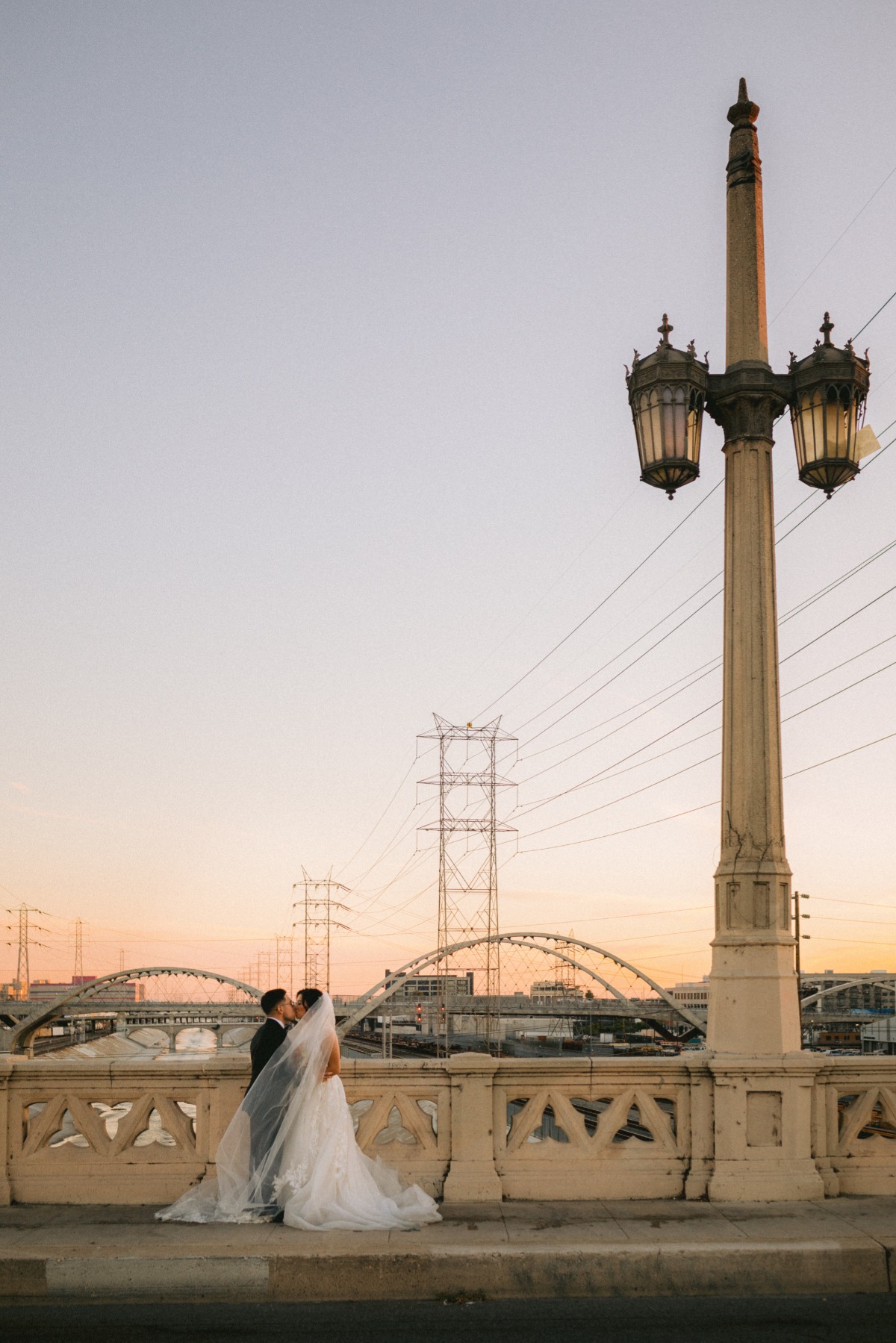 bride and groom kiss on bridge in LA