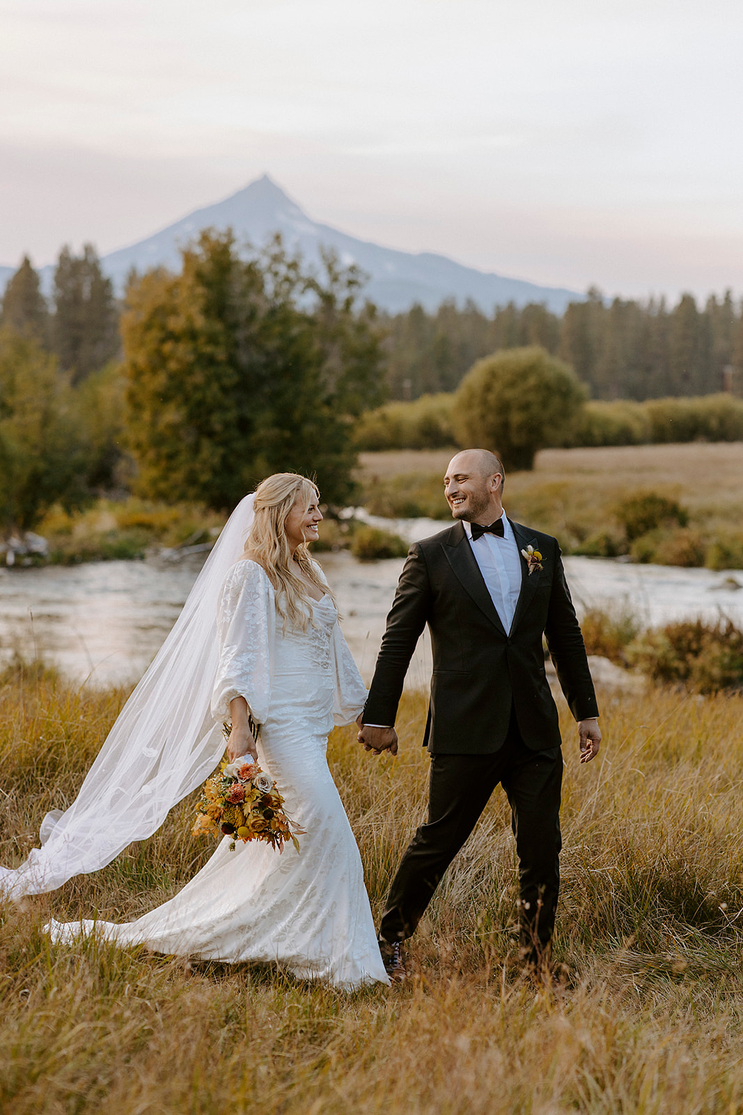 bride and groom walking through wildflower meadow