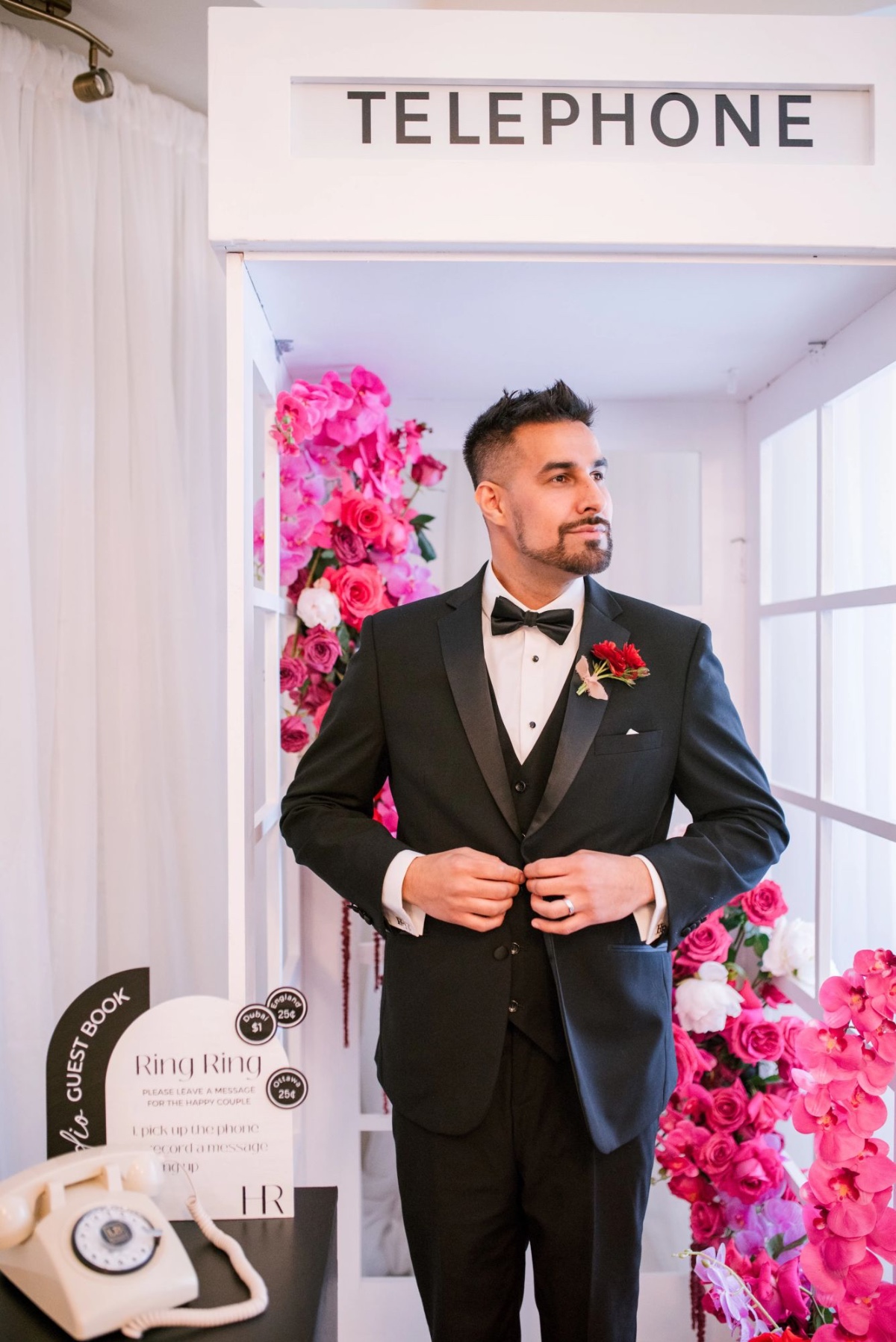 groom poses in front of telephone booth and audio guestbook