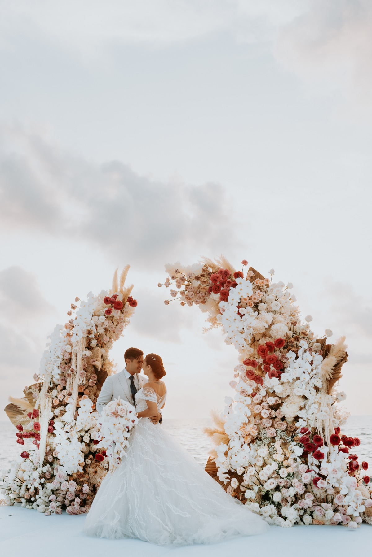 waterfront sunset wedding with earth tone floral arch