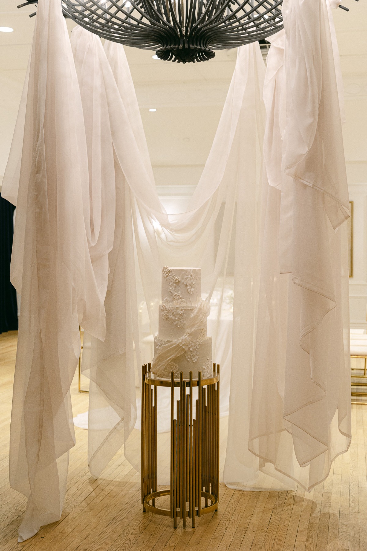 all-white wedding cake surrounded by tulle drapery