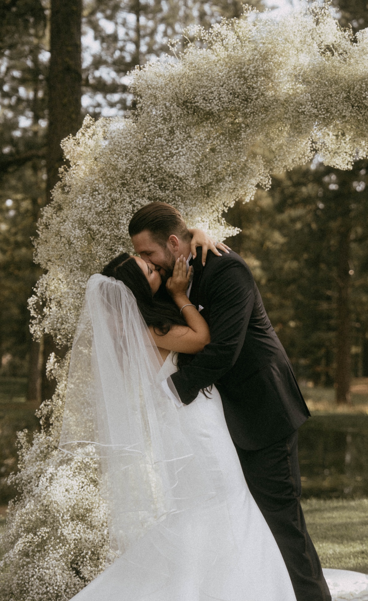 bride and groom kiss under babys breath altar