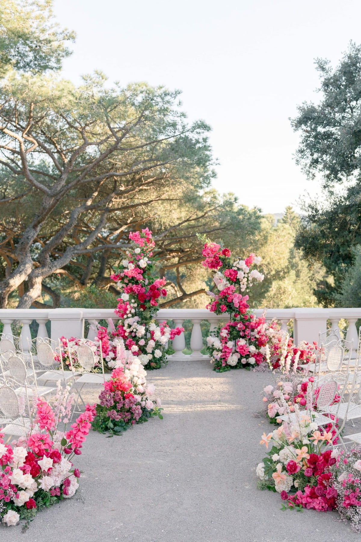 pink wedding ceremony with big floral arch and white chairs