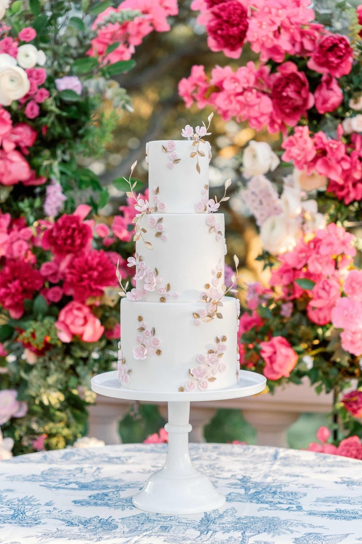 three tiered wedding cake with gold and pink flower details