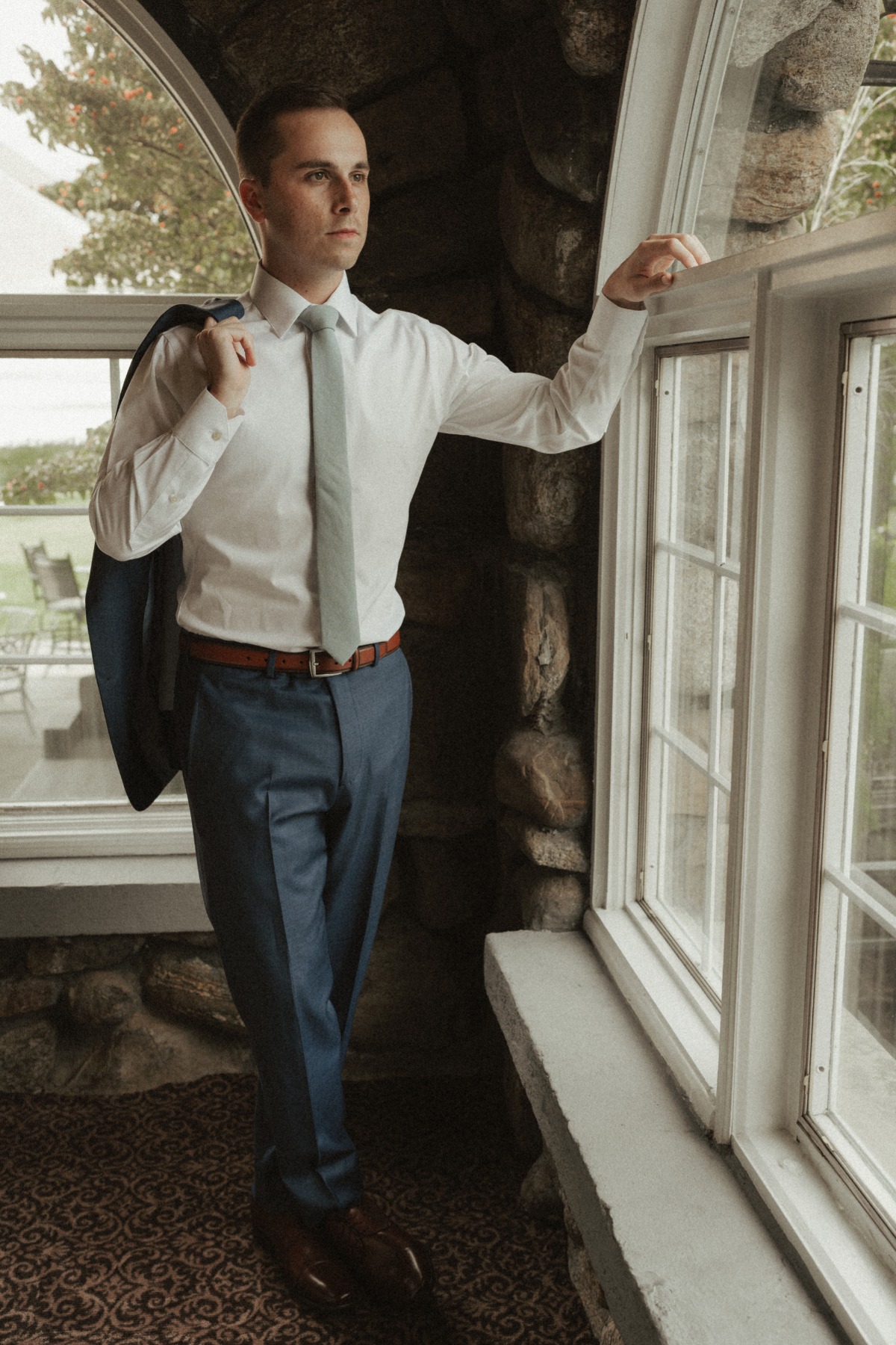 groom getting ready in blue suit with mint tie