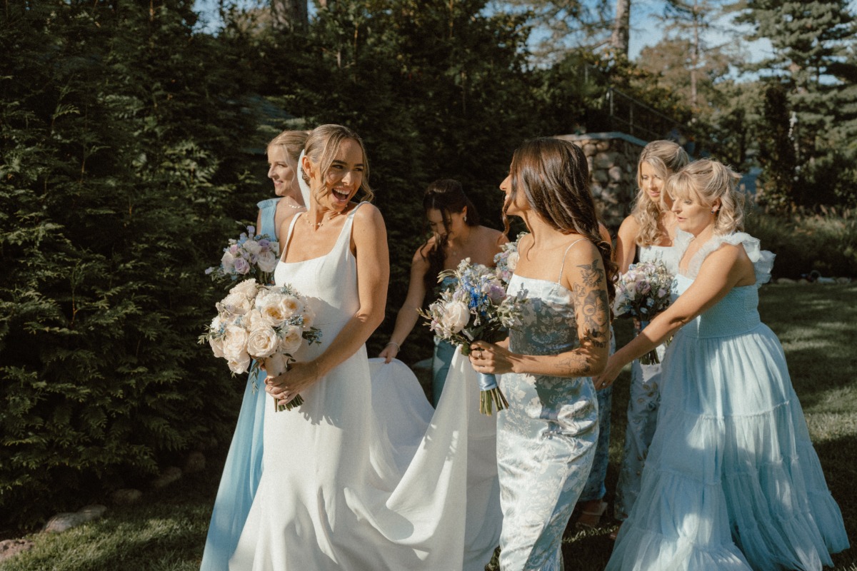 bridesmaids in blue dresses hold train for bride