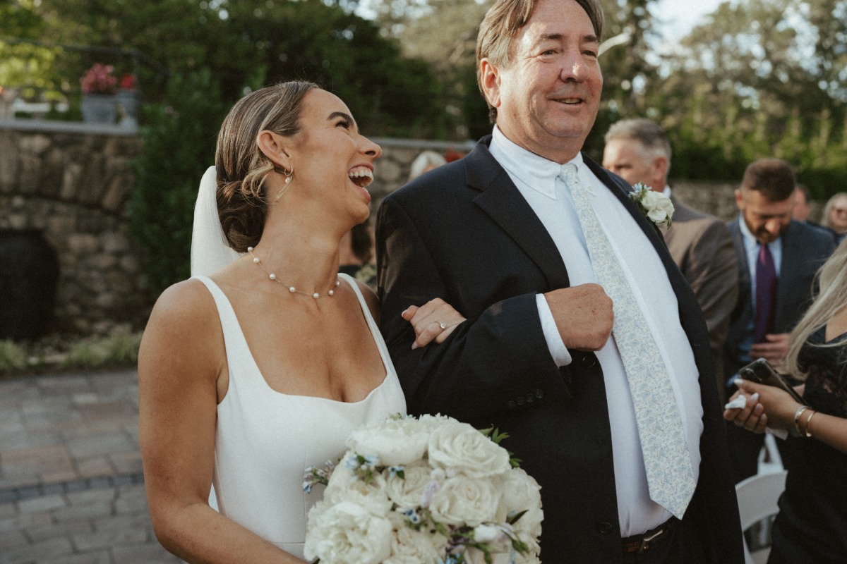 bride laughing as her father walks her down the aisle