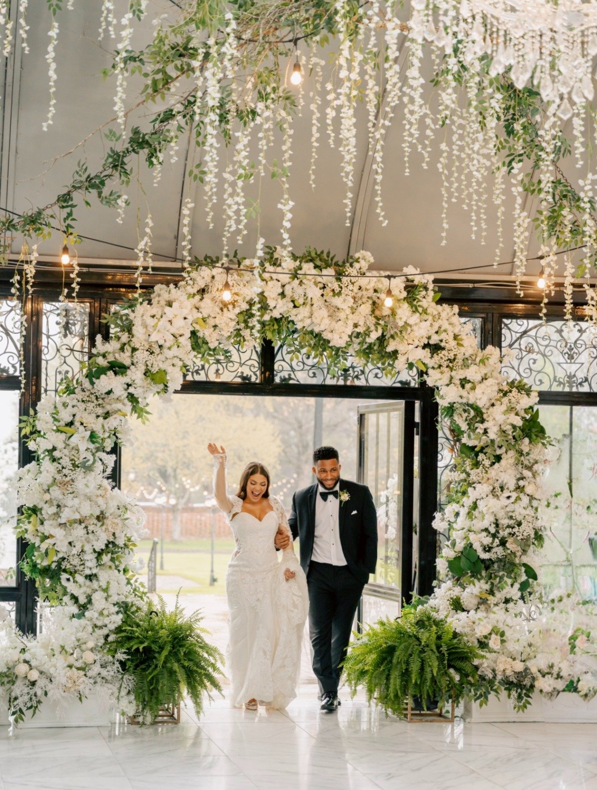 all-white floral arch with ferns