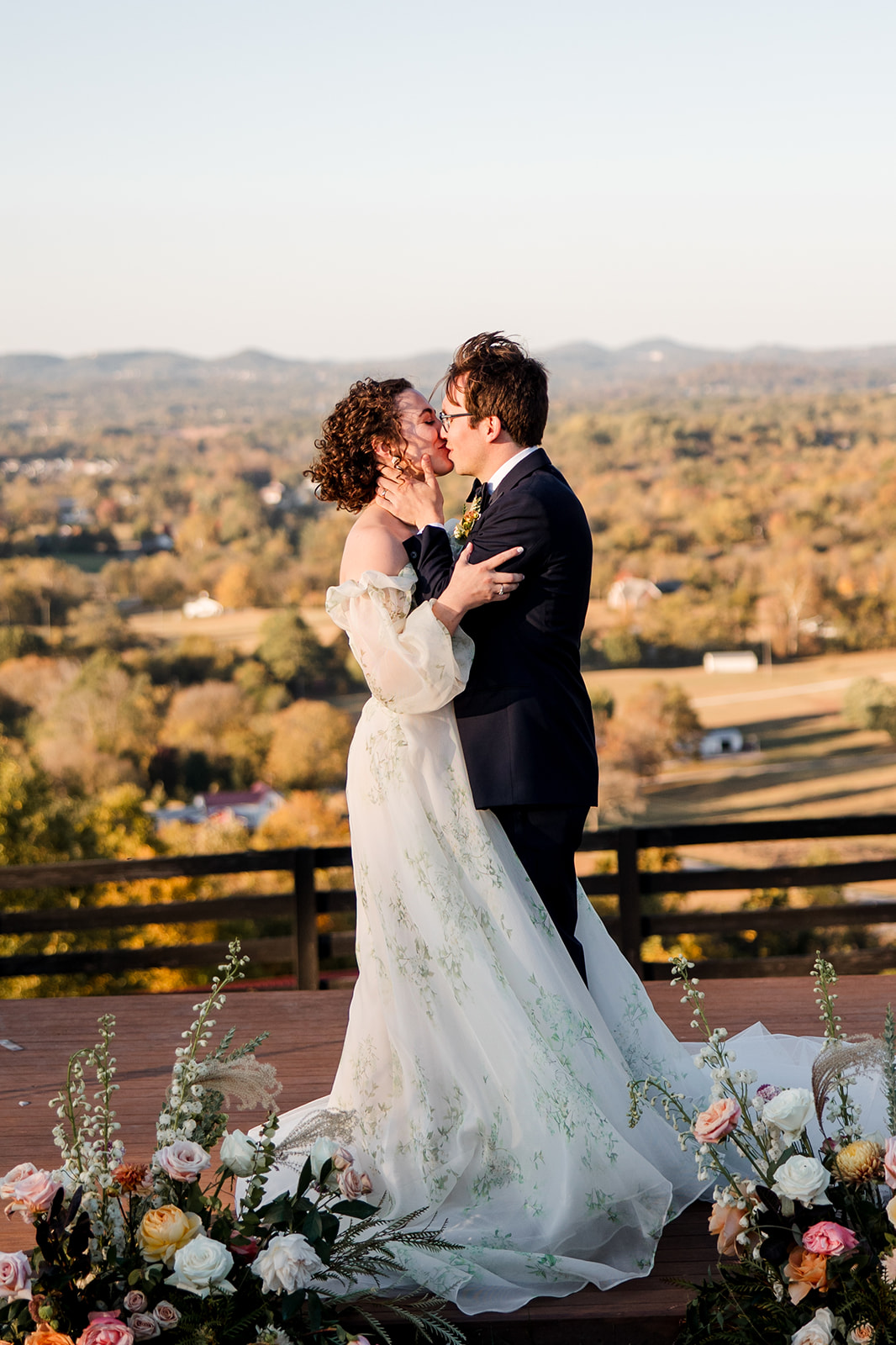 bride and groom kiss with fall hillside in the background