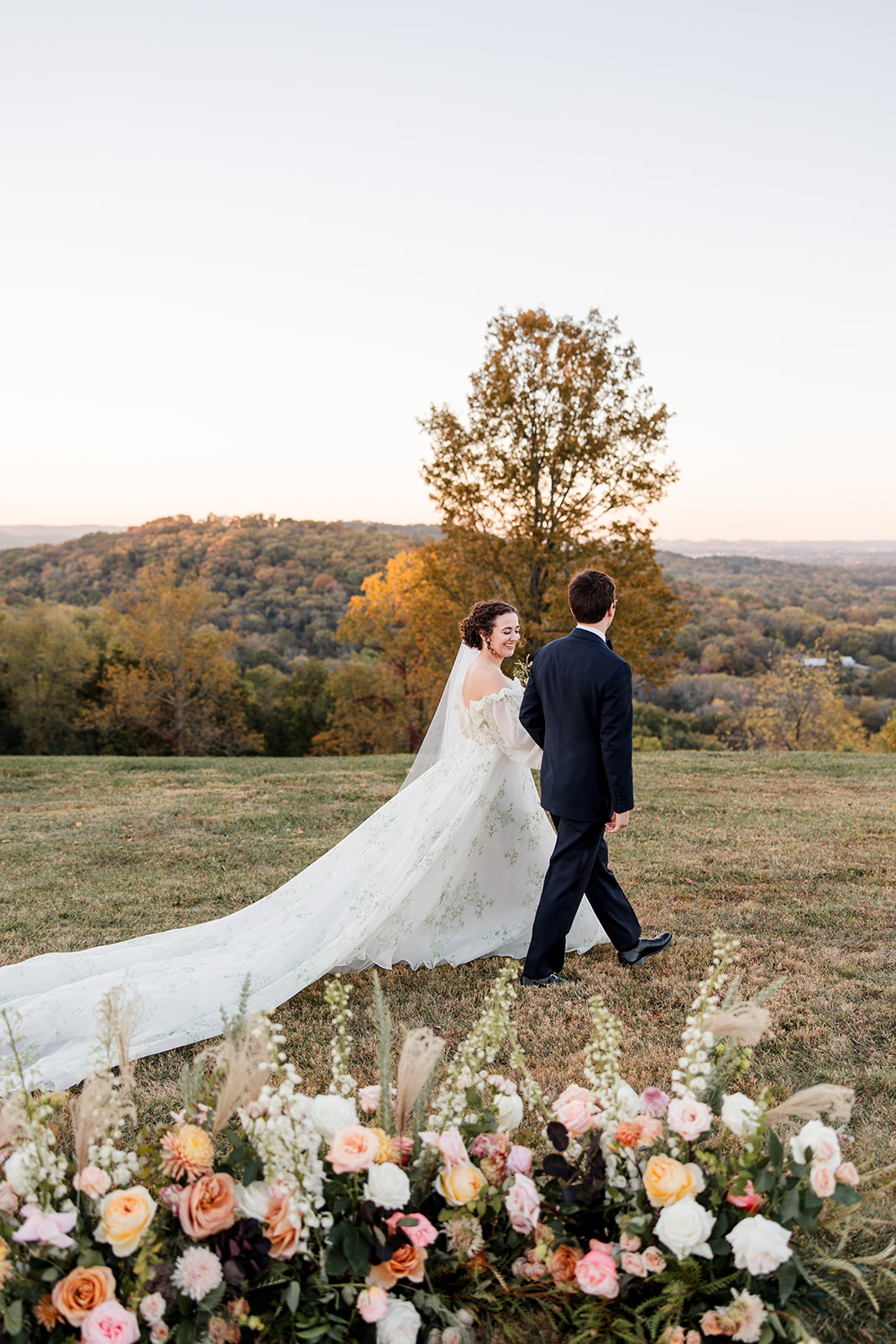 bride and groom walking through the fall countryside