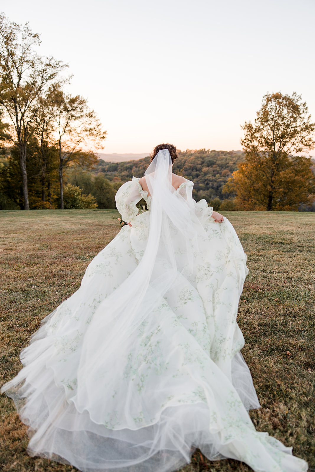 bride in printed gown running through the countryside