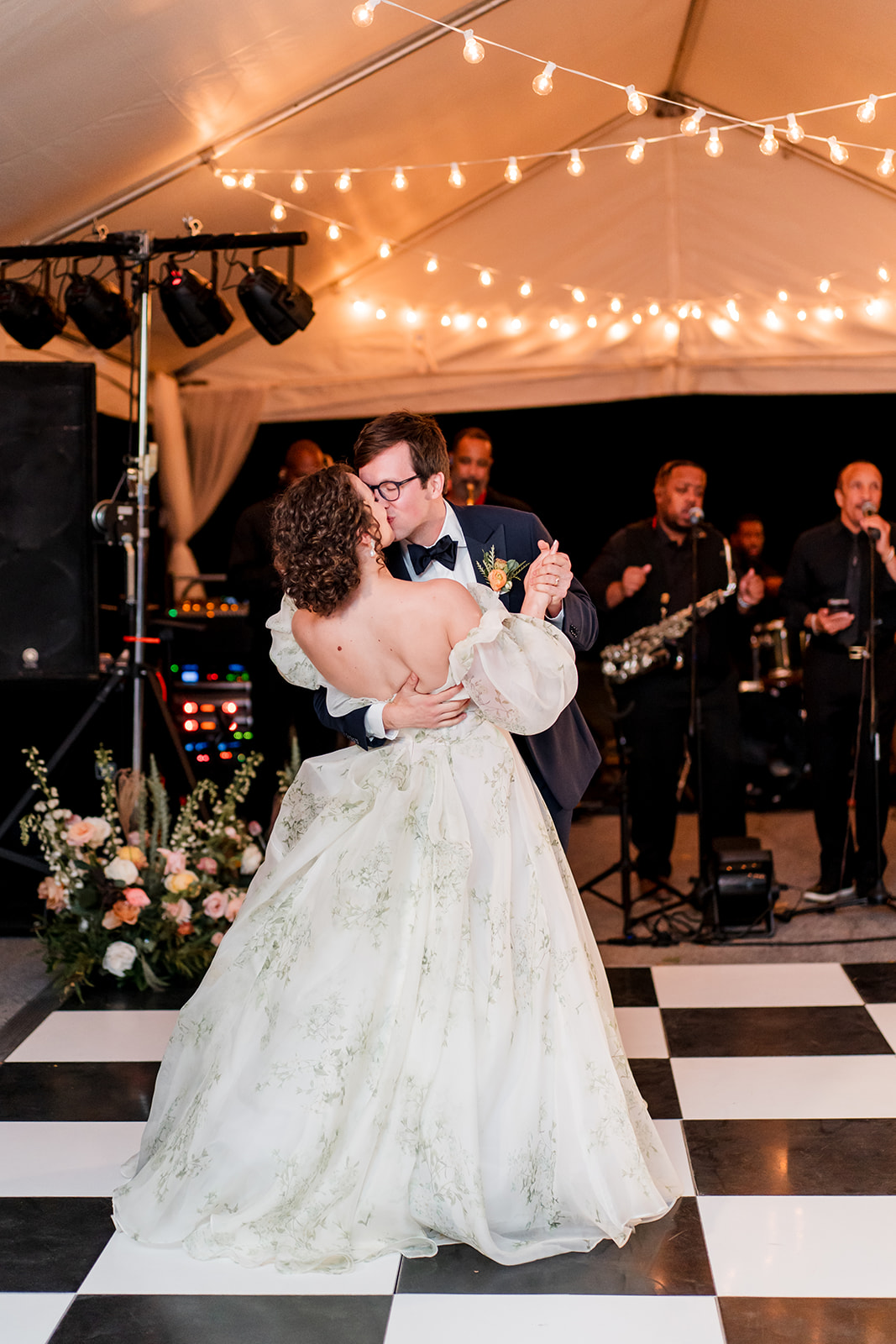 bride and groom dancing in tented reception with band and checkered floor