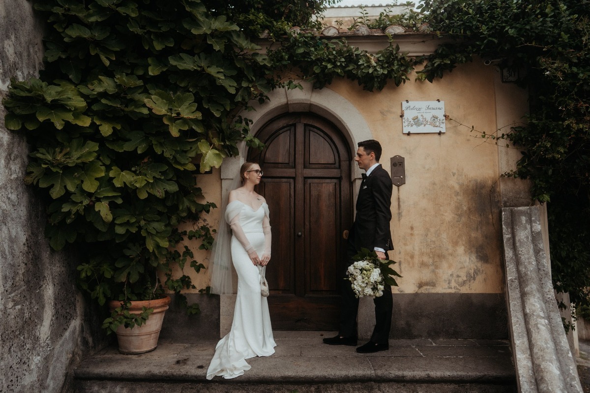 bride and groom pose by vintage door in positano