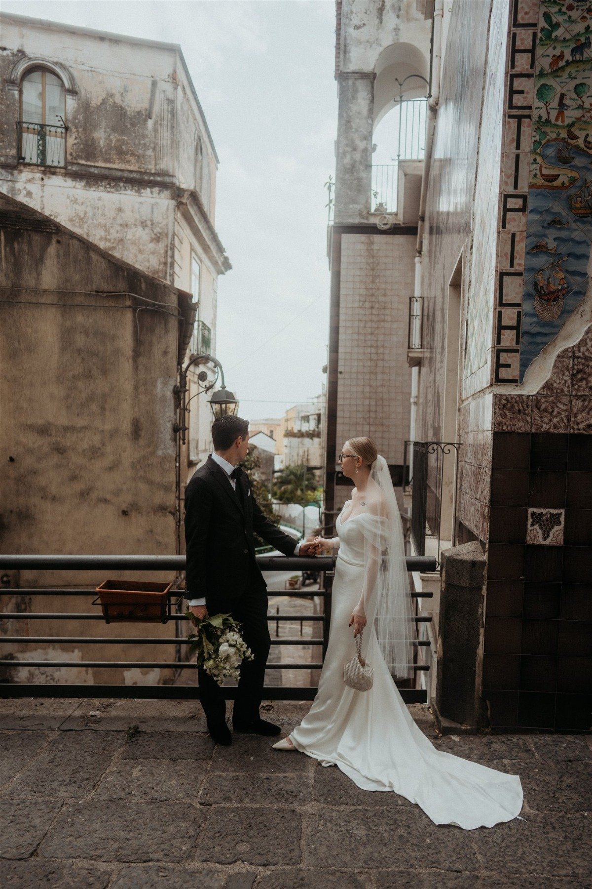 bride and groom look off of balcony in positano