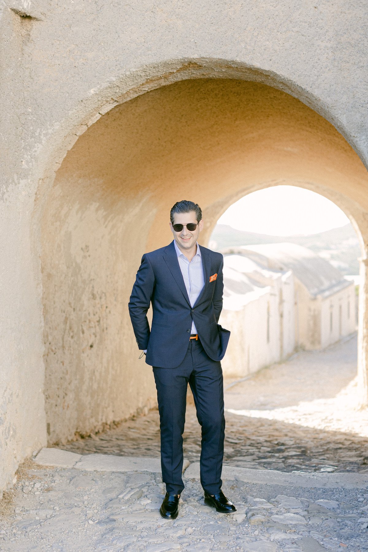 groom in blue suit with orange accessories on greek island