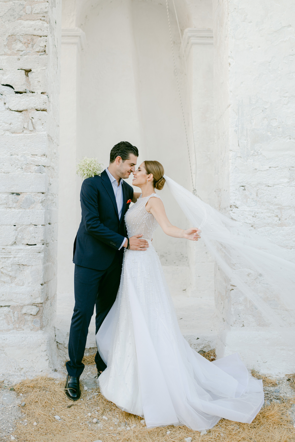 bride and groom at wedding in greece with veil blowing in the wind