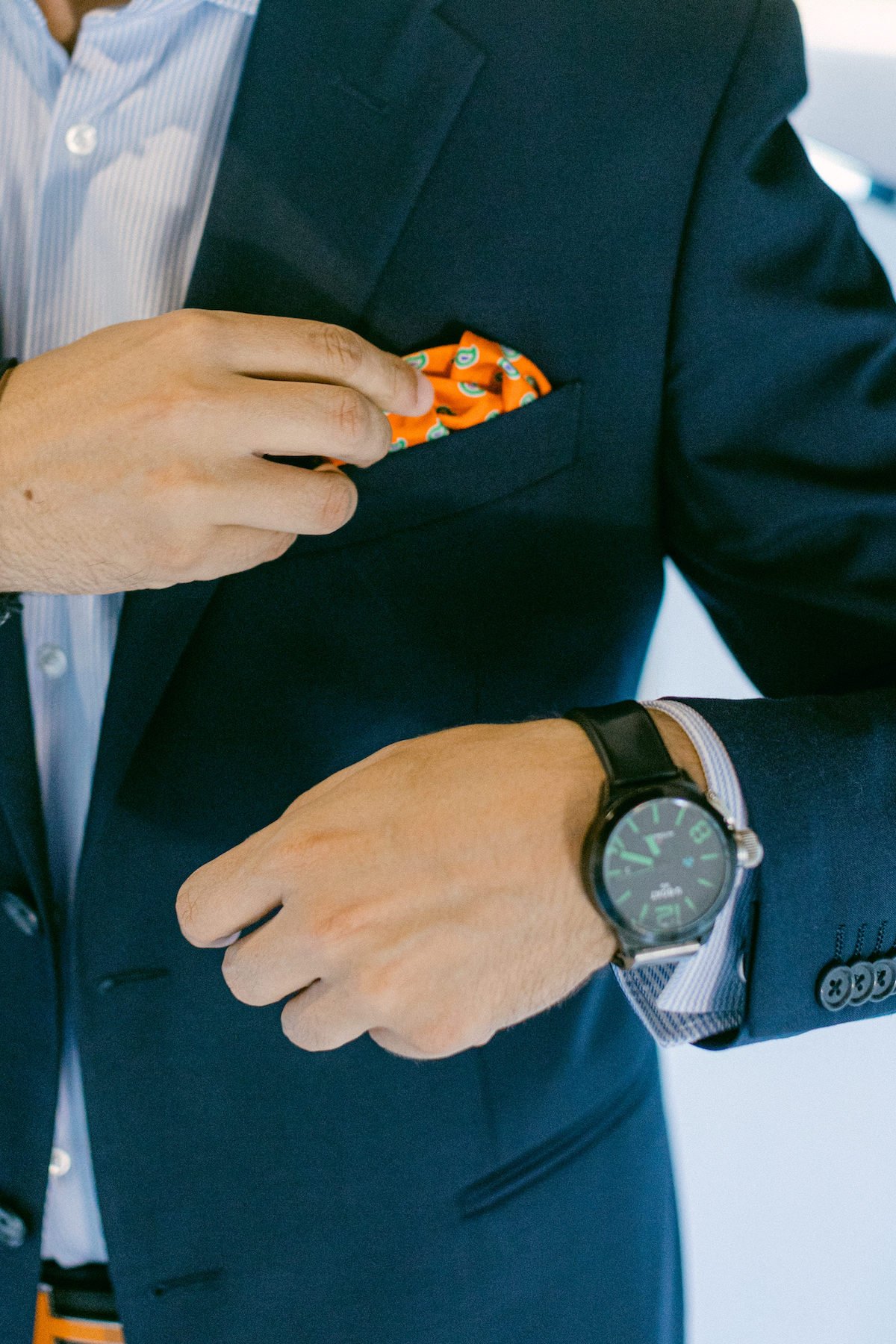 groom in navy blue suit with orange accessories