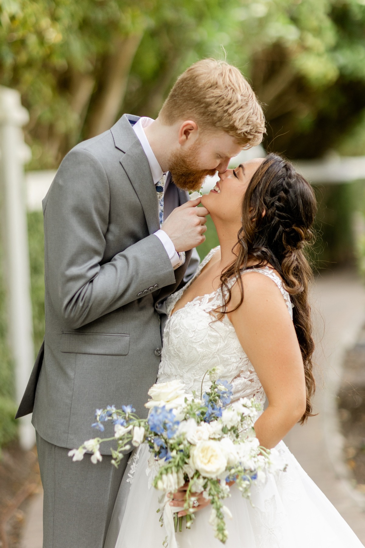 bride and groom in gray suit with blue and white flowers