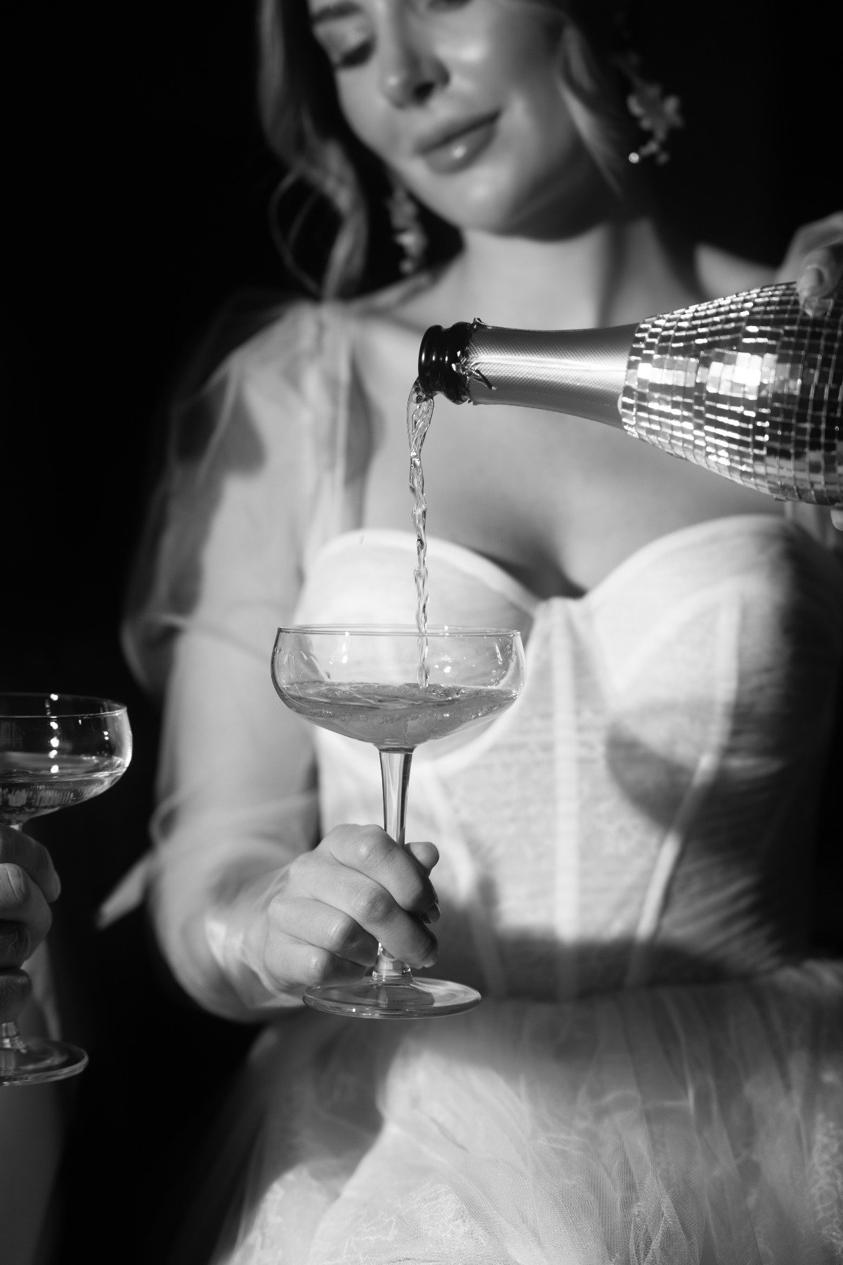 bride pouring champagne into a coupe glass