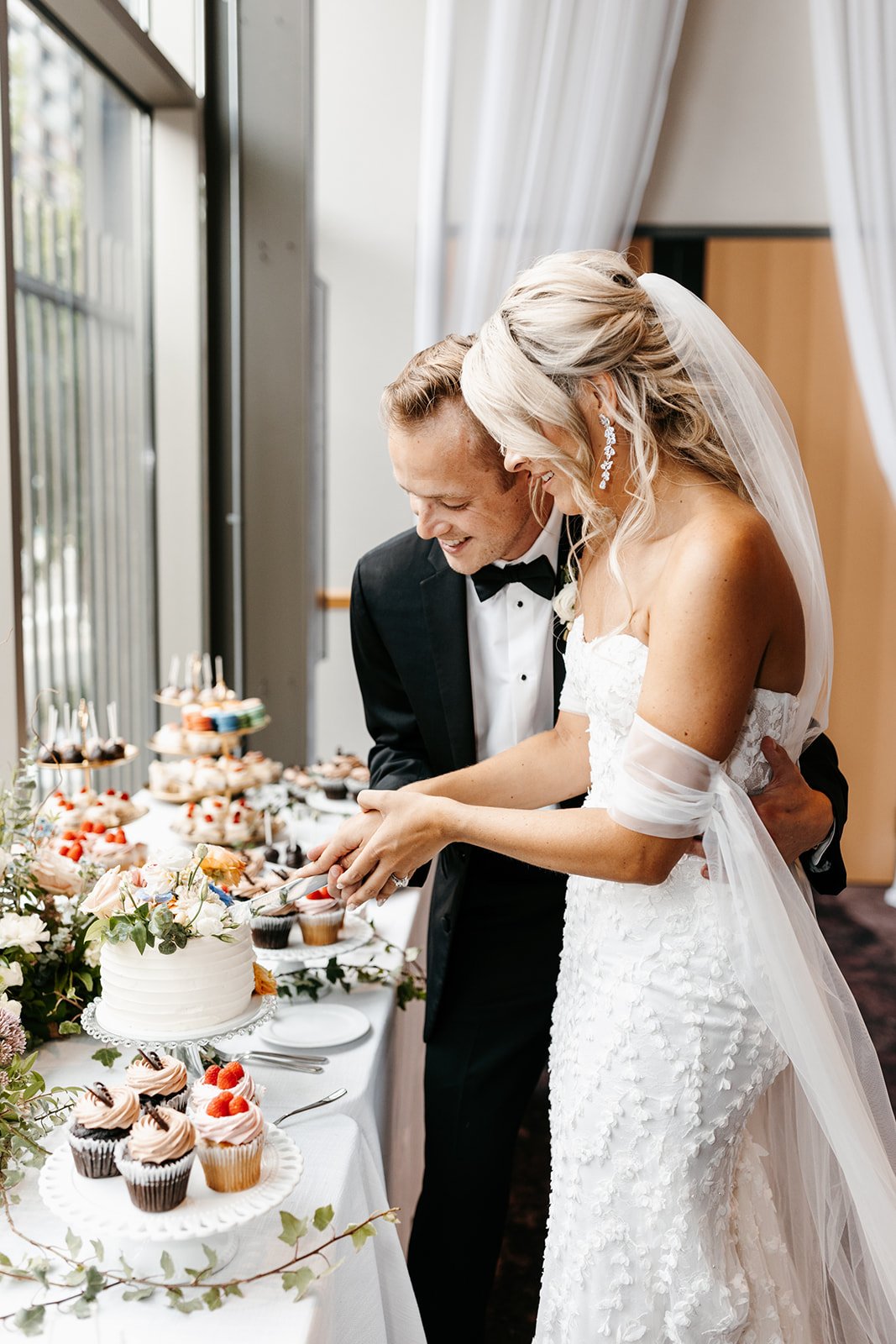 bride and groom cutting simple wedding cake on dessert table