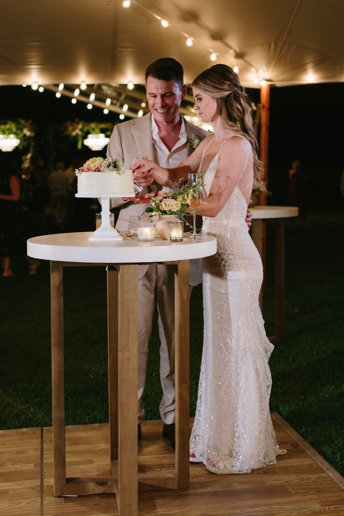 bride and groom cut simple buttercream wedding cake in tent