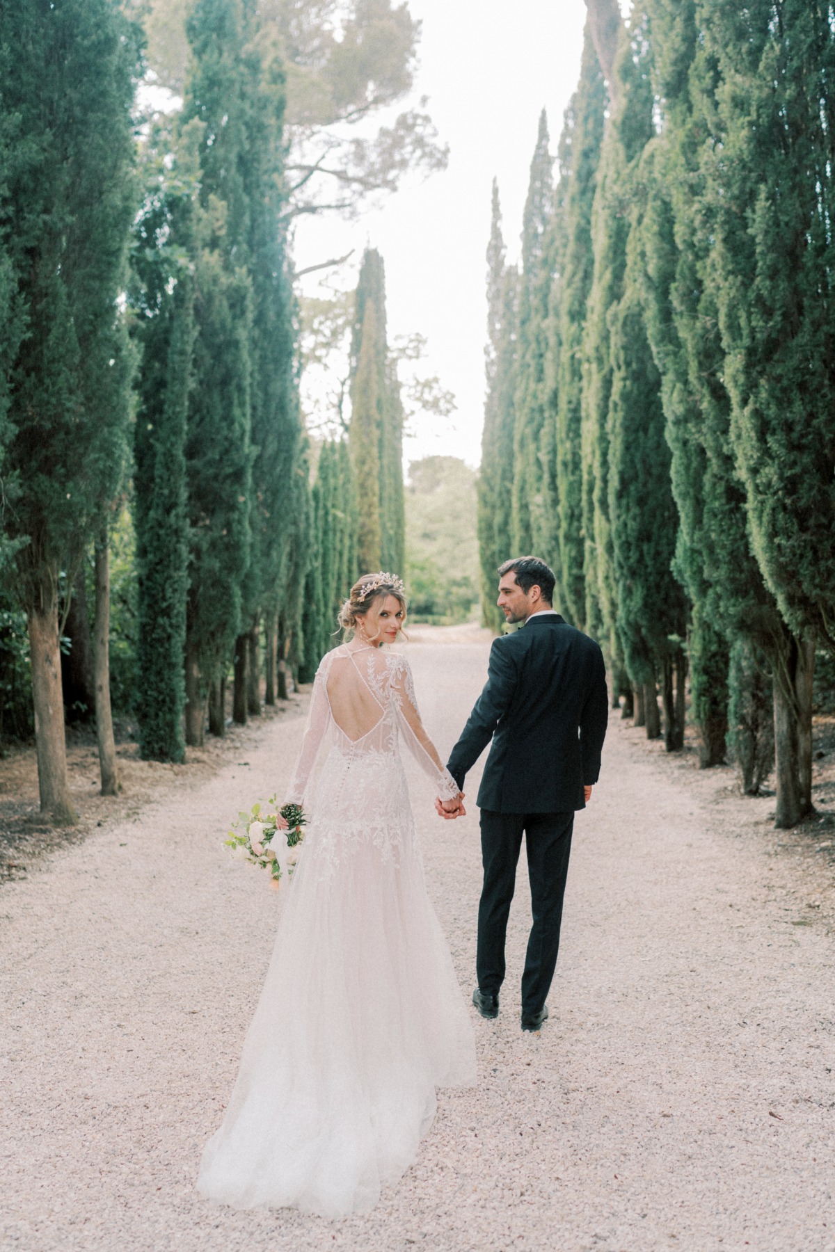 bride in backless dress with groom walking in garden in provence